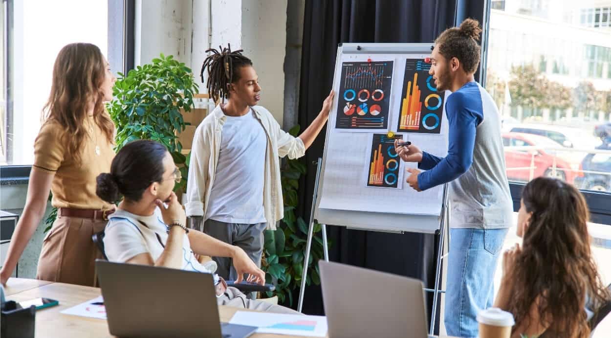 Group of coworkers analyzing graphic charts on a board