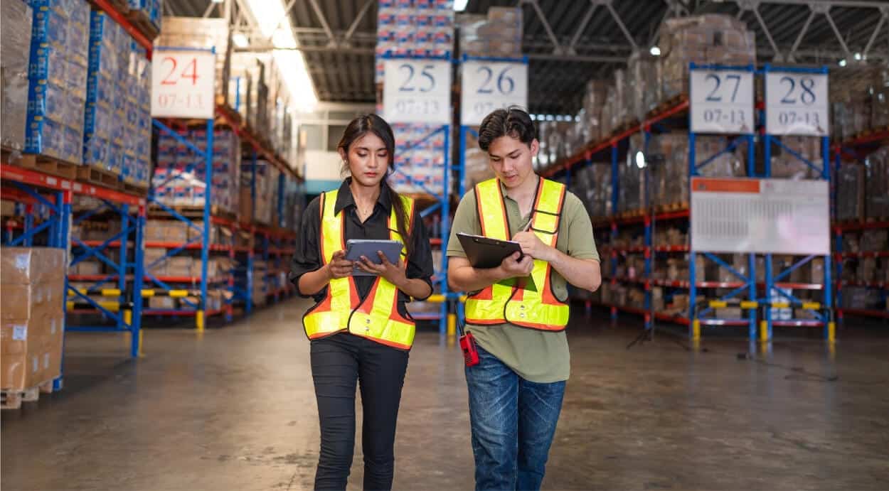 Warehouse workers using digital tablets to manage inventory data, illustrating real-world application of Days Sales in Inventory (DSI) calculation