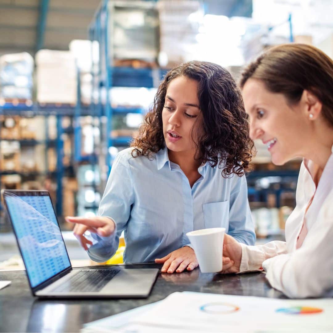 People looking at laptop in warehouse