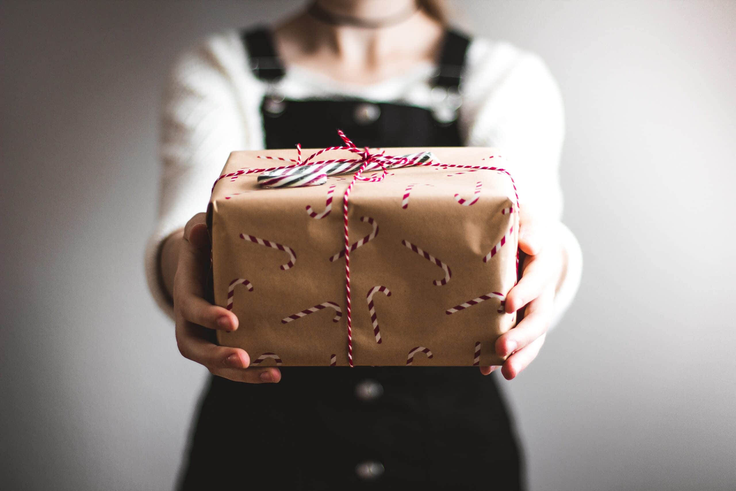 Person holds gift wrapped box in foreground