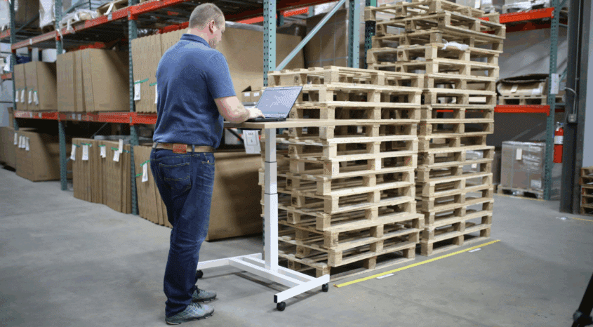 A man records inventory counts on a laptop computer in a warehouse