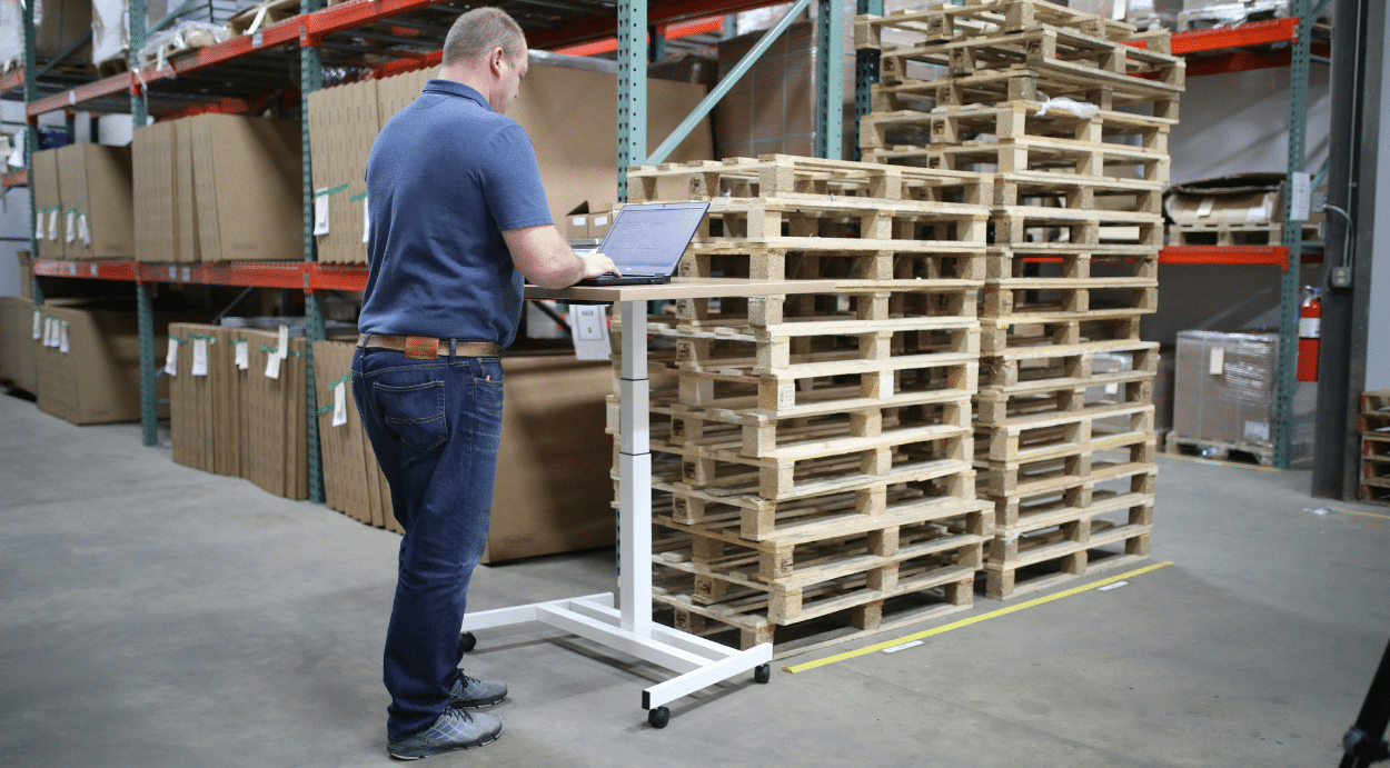 A man records inventory counts on a laptop computer in a warehouse
