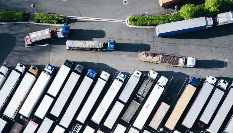Overhead view of semi-trucks and trailers arranged in rows at a distribution center, showcasing 3PL transportation capabilities.